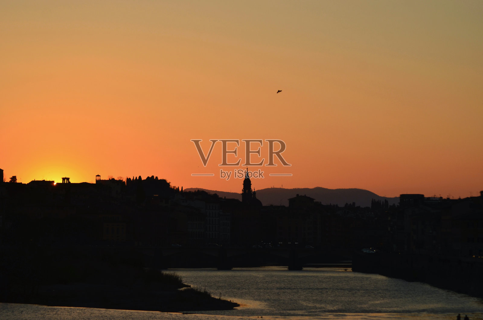 佛罗伦萨和阿尔诺河的日落，天空中有一只鸟。照片摄影图片
