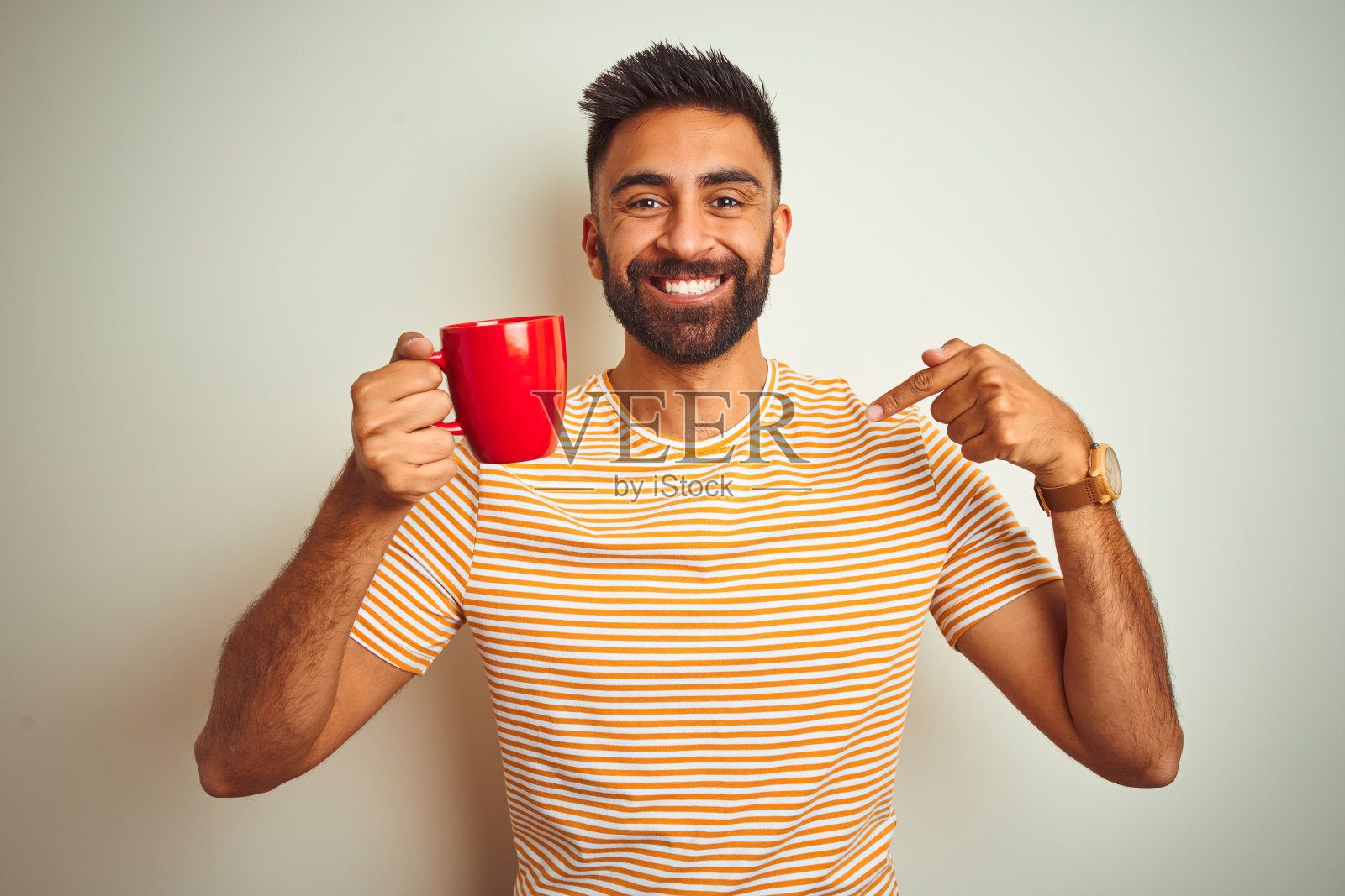 年轻印度男人喝咖啡，惊讶地指向自己照片摄影图片