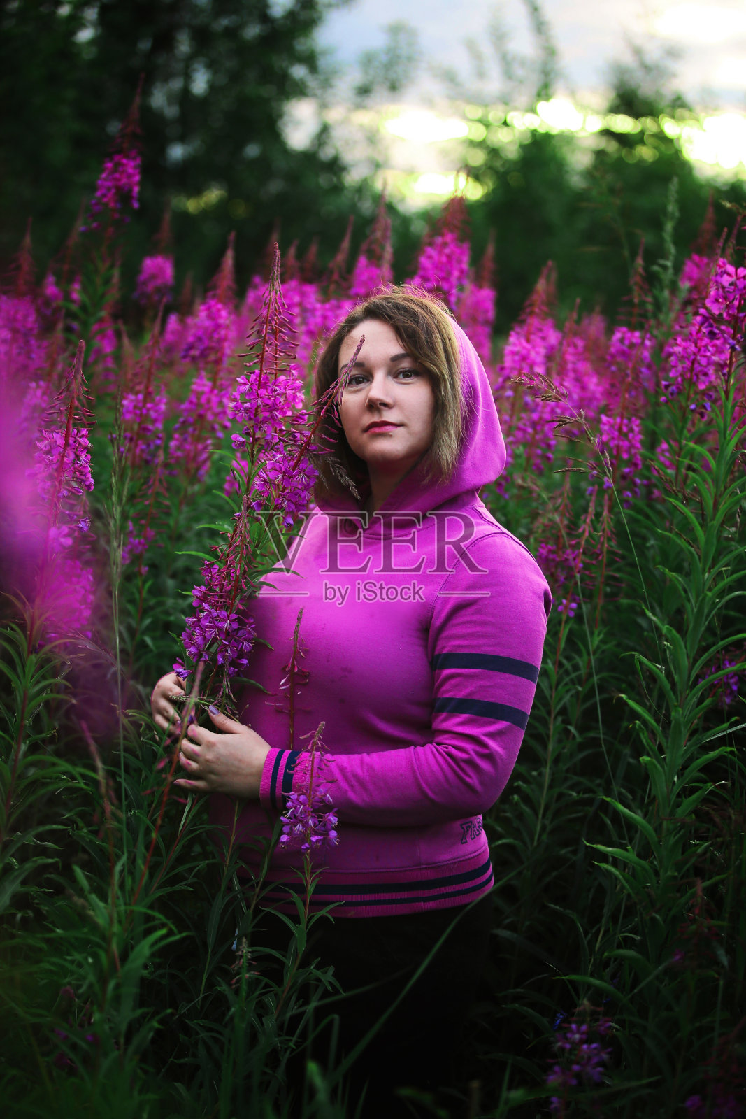 在草地鲜花丛中穿帽衫的女人照片摄影图片