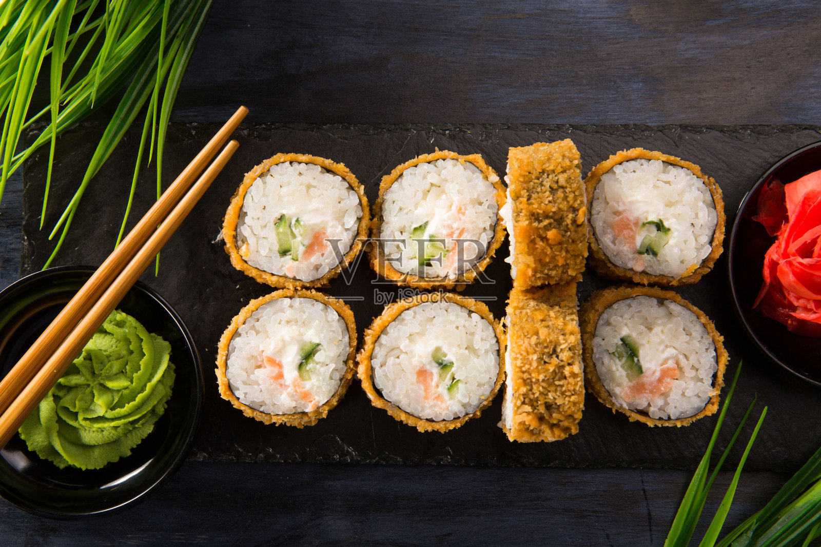 一套烤寿司卷与芥末和生姜在黑色的背景。日本东方美食照片摄影图片