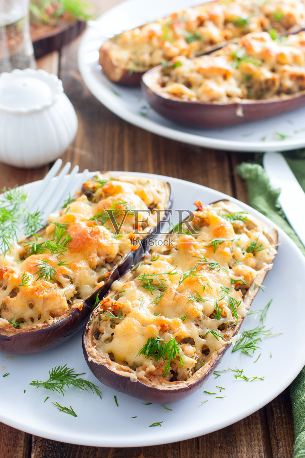 烤茄子与肉末奶酪在一个白色的盘子在木桌上，选择性的焦点照片摄影图片