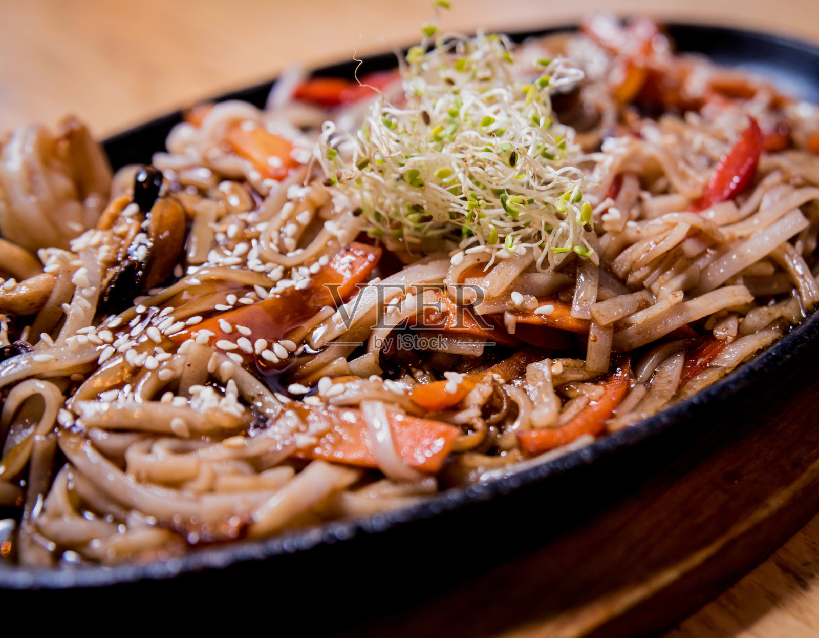 木桌上放着中式面条、贻贝和虾。照片摄影图片