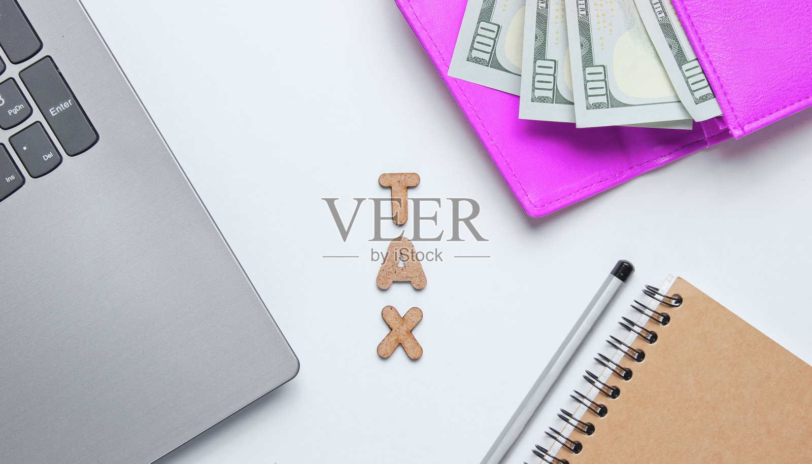 创意商业概念：笔记本电脑、笔记本、铅笔、钱包和美元纸币在白色背景上，木制字母拼写的“税务”字样，简约风格照片摄影图片