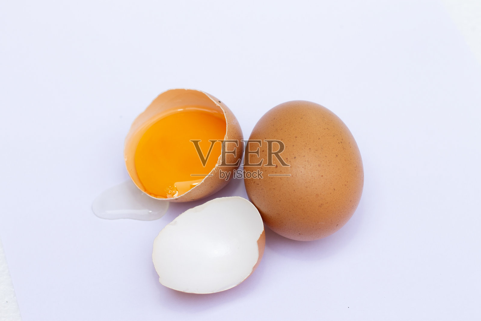 两个棕色鸡蛋，一个破裂，蛋黄和蛋白流出照片摄影图片