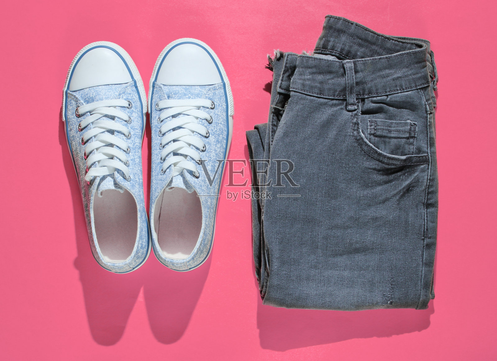 简约时尚的概念。粉色背景上的时尚运动鞋和牛仔裤。俯视图照片摄影图片