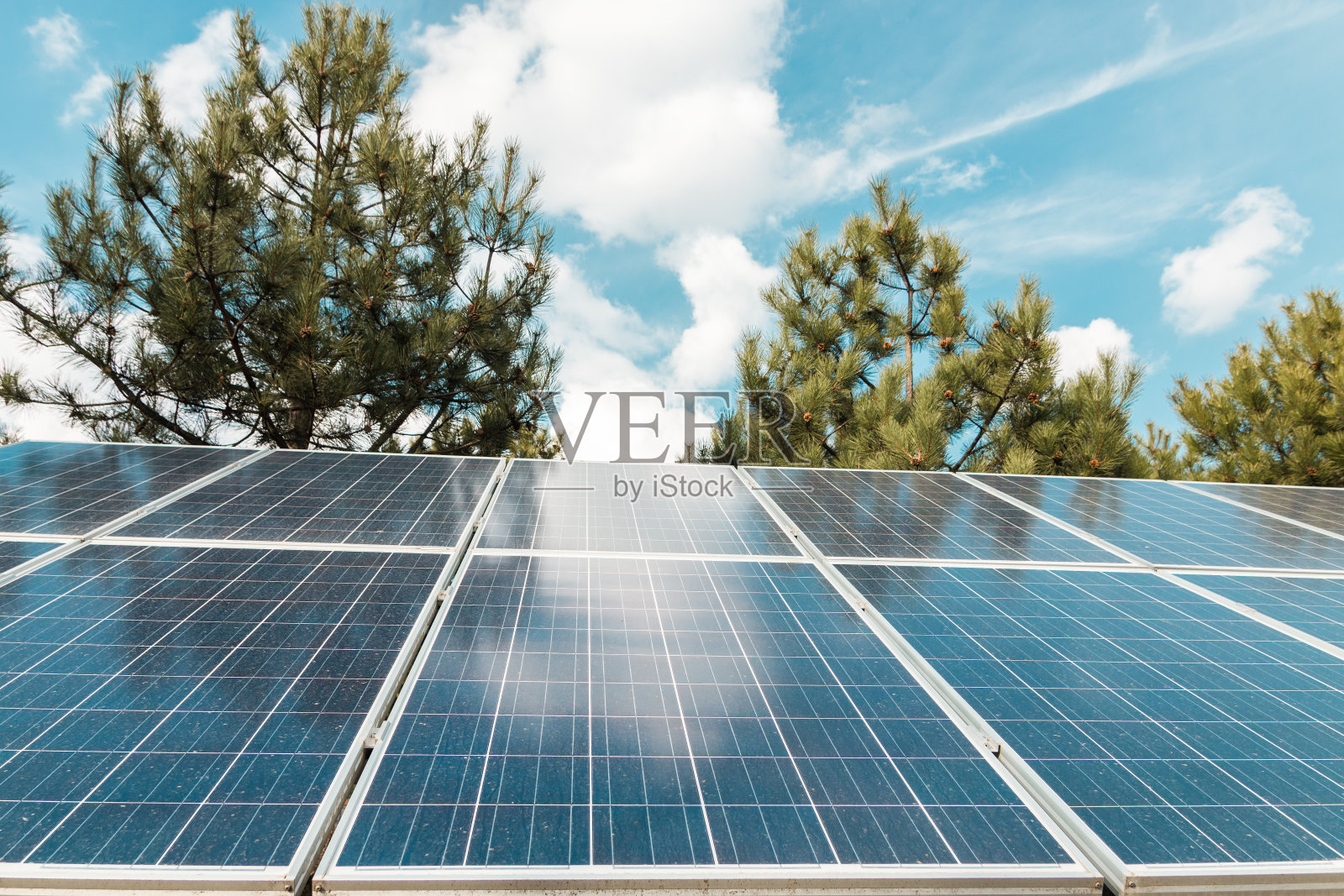 蓝天绿树之上的太阳能电池板。生态替代能源生产照片摄影图片