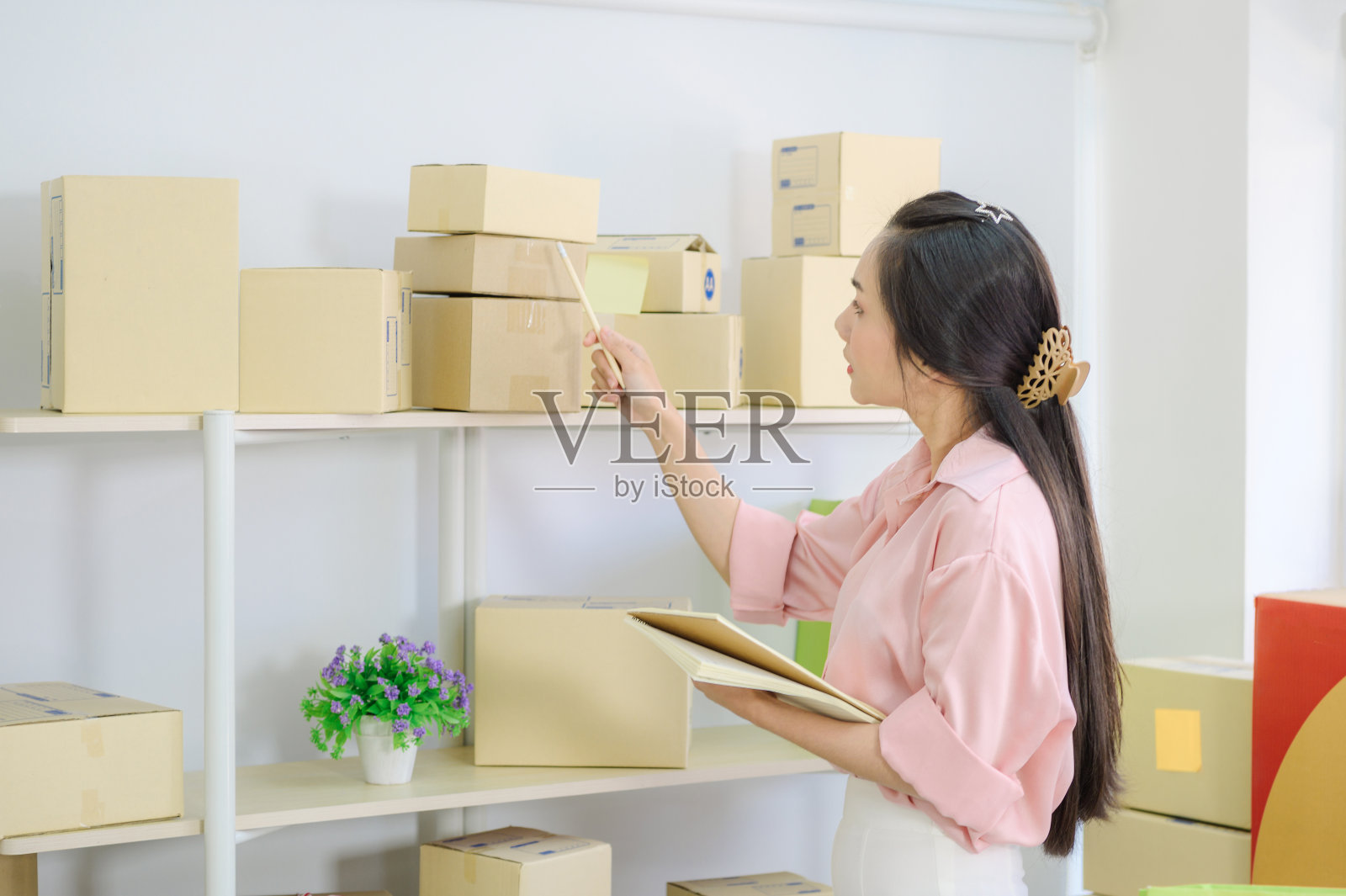 年轻漂亮的青少年在家工作，在包裹盒上写字。新一代年轻创业者的生活方式照片摄影图片