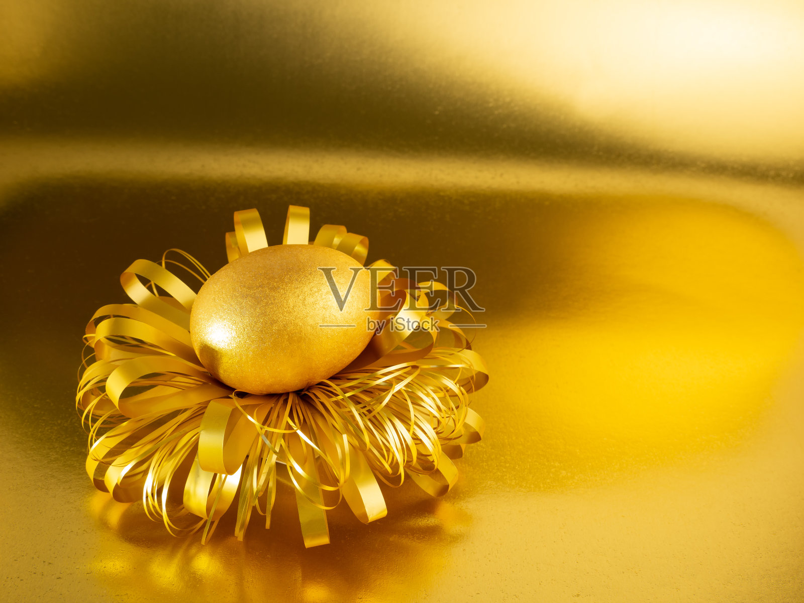 一个涂着金色和黑色的复活节彩蛋躺在一个闪闪发光的金色背景上的蛋窝里照片摄影图片