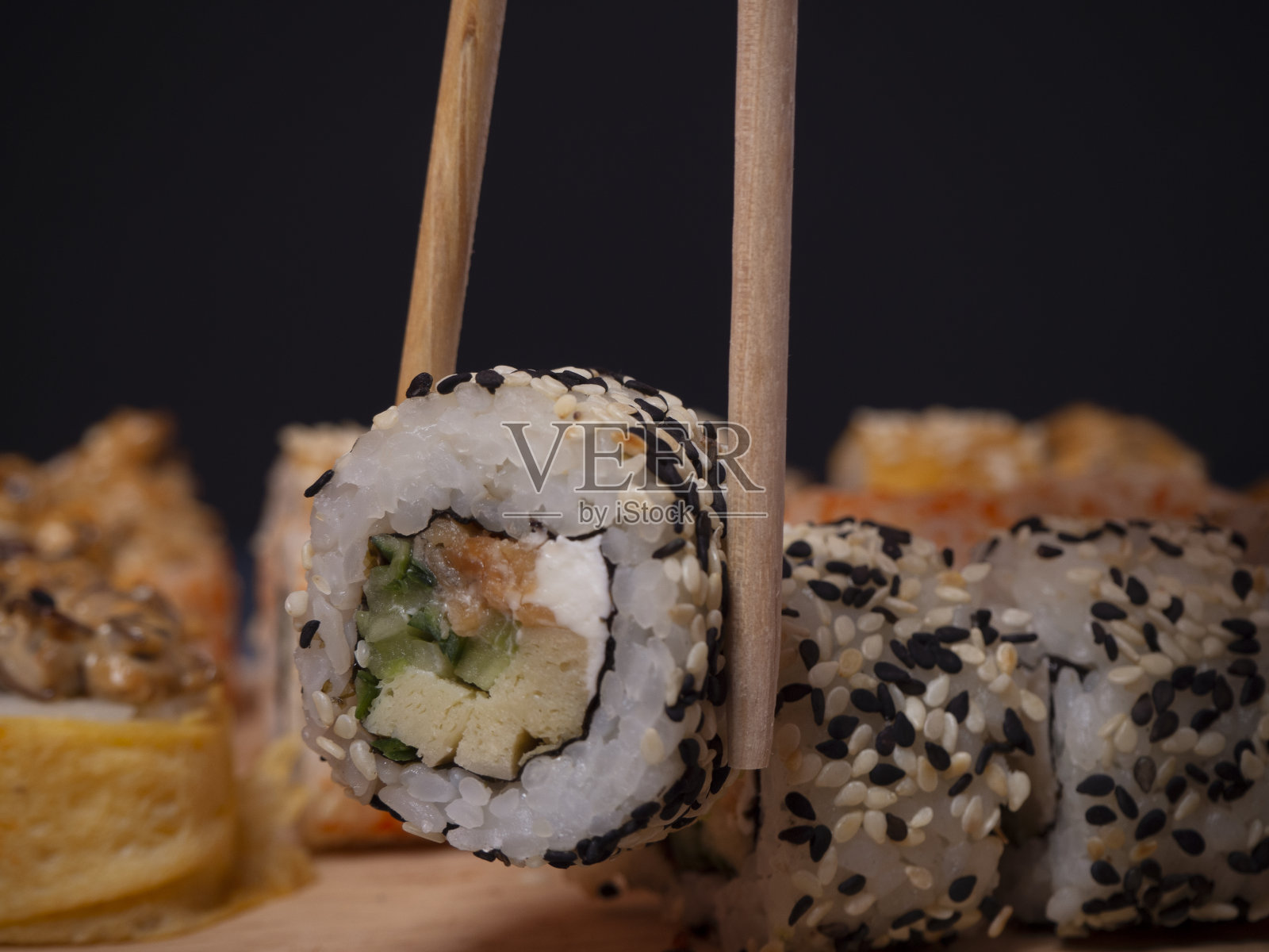 寿司卷配红烧三文鱼，奶油芝士，墨西哥蛋卷，蟹肉奶油，鳄梨和芝麻。照片摄影图片