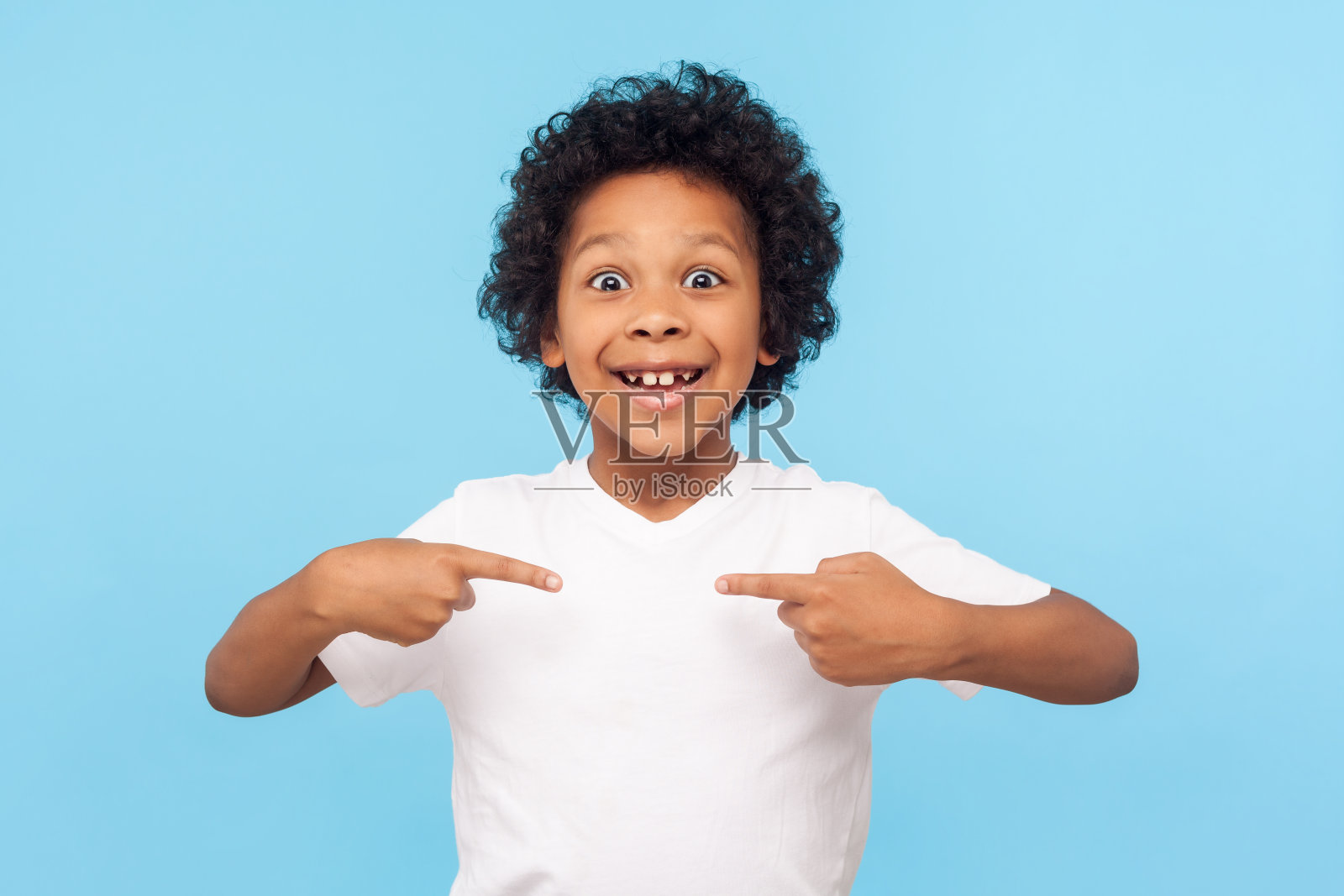 哇，这就是我!这是一幅穿着t恤的学龄前男孩惊讶快乐的照片，他吃惊地看着镜头，指着自己照片摄影图片