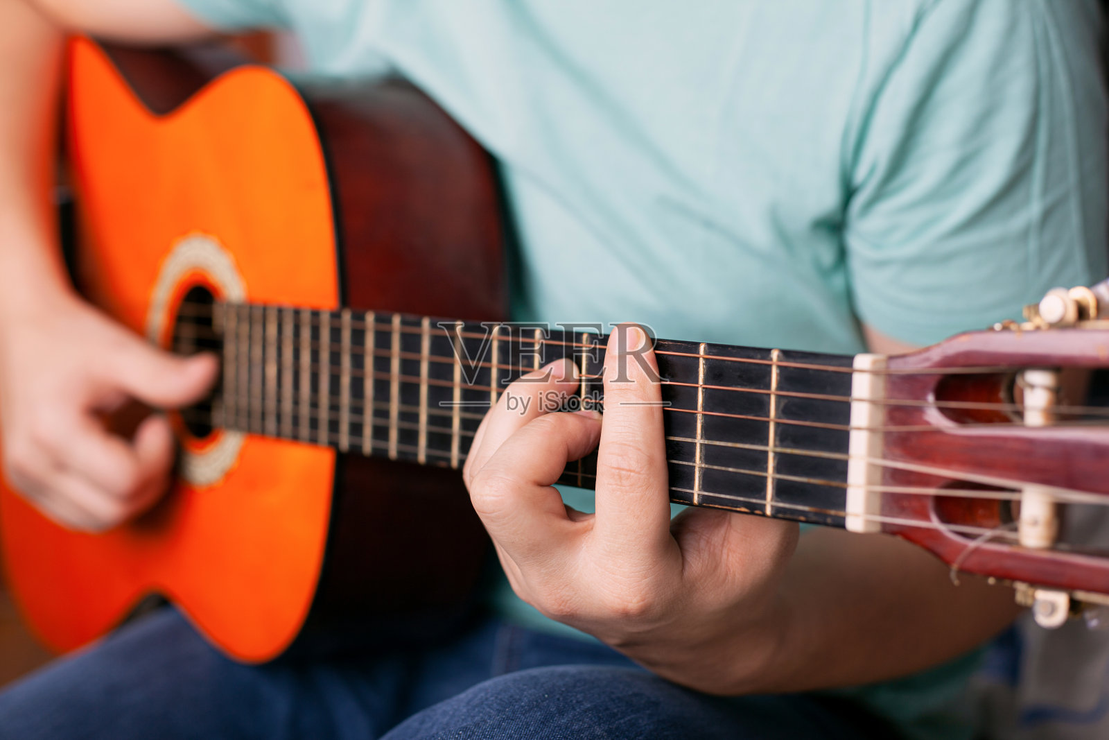 男人弹奏原声吉他，手指按住和弦，学习演奏乐器照片摄影图片
