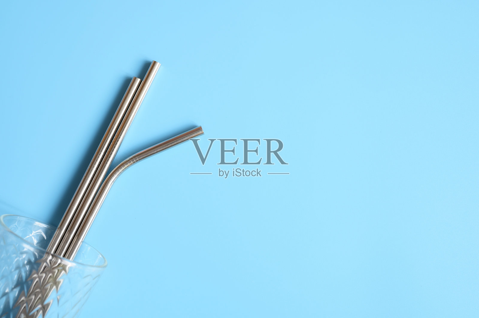 可重复使用的金属不锈钢吸管玻璃上的蓝色背景。空间的文本照片摄影图片