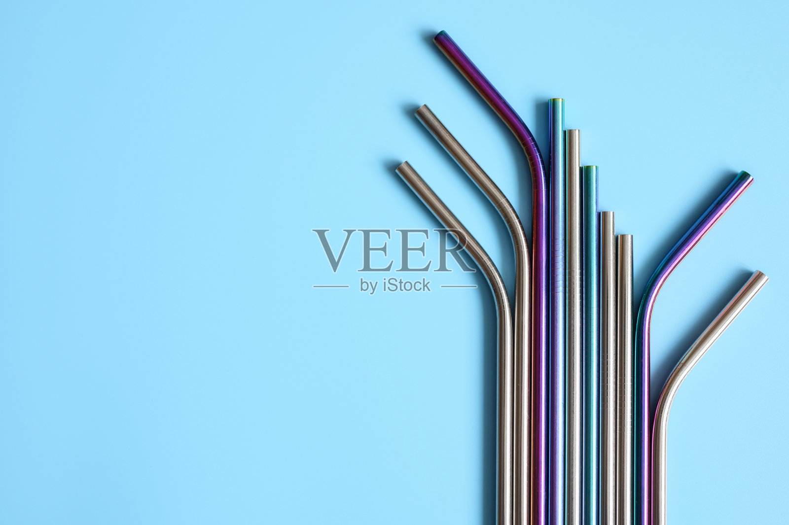 几根可重复使用的金属不锈钢吸管，蓝色背景。空间的文本照片摄影图片