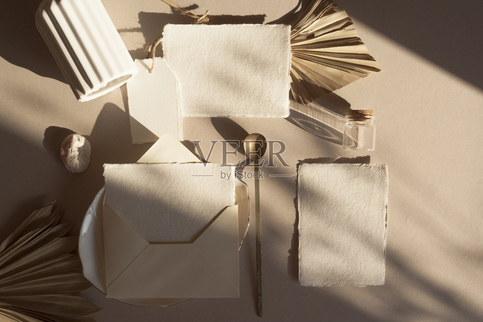 空白的白色婚礼问候邀请卡模型与工艺信封，标签，干燥的热带棕榈叶，花瓶盘子，在木制纹理的桌子背景。优雅的现代模板。平放俯视图照片摄影图片