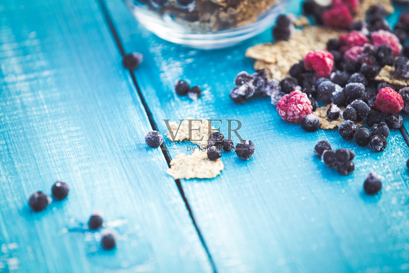 蓝色木质背景上的有机谷物和森林浆果照片摄影图片