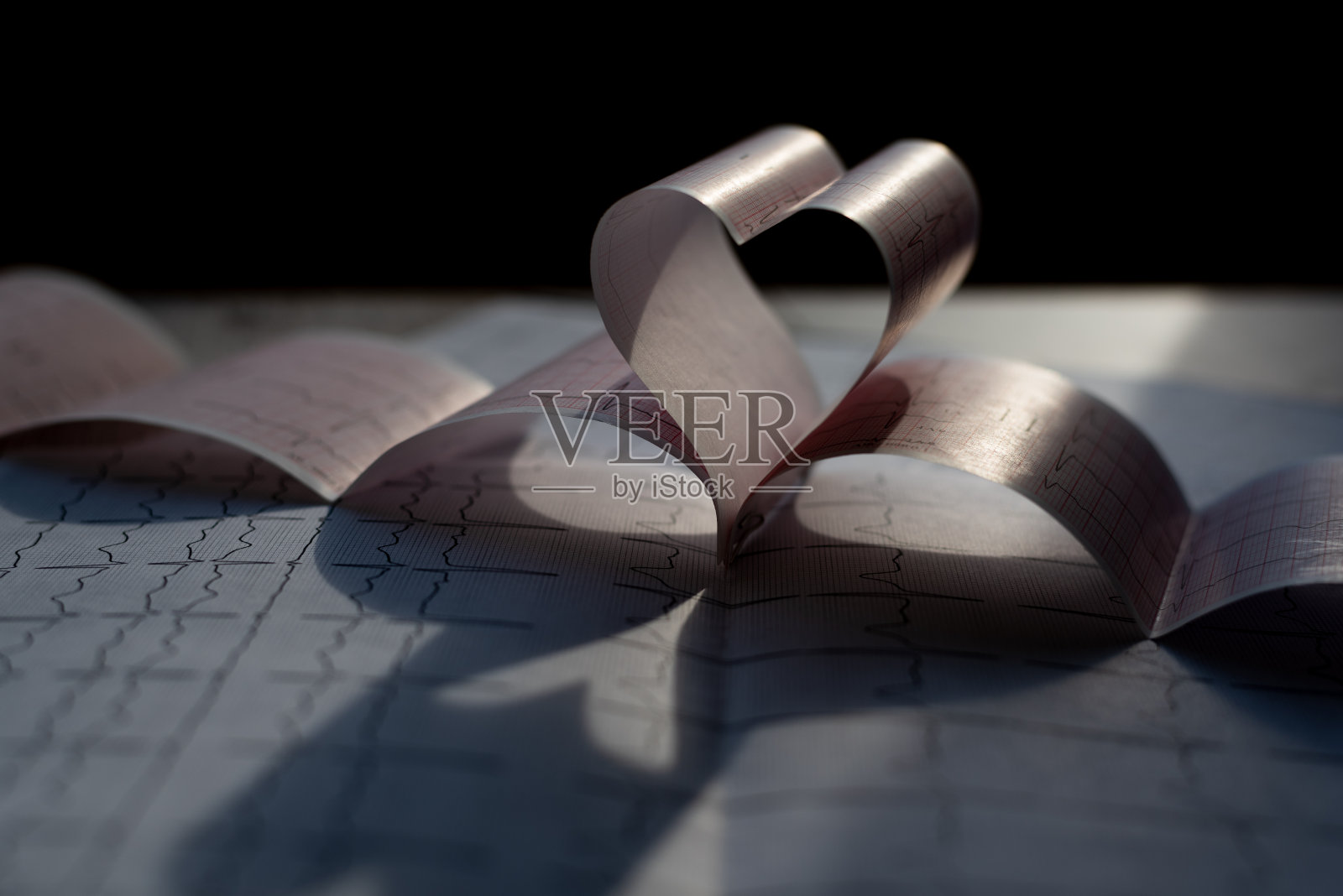 心脏形状的心电图打印在黑暗中。心脏检查的概念。医学背景。特写镜头照片摄影图片