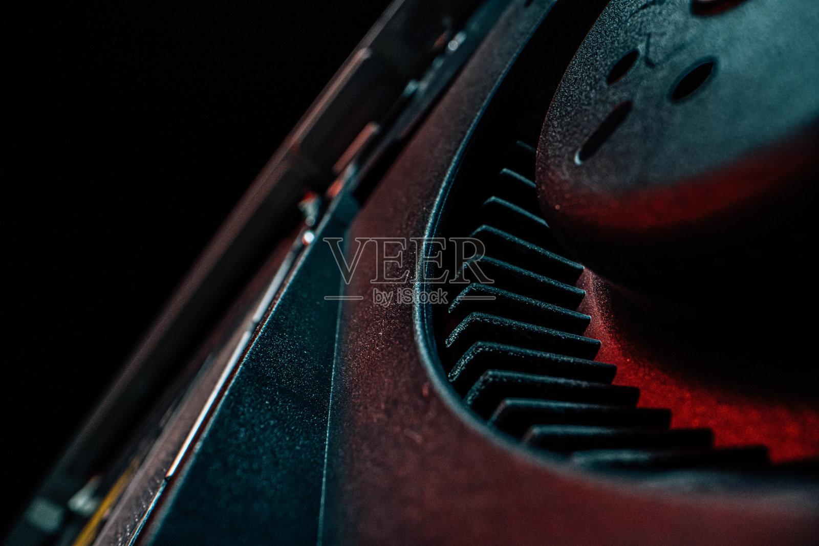 艺术微距特写拍摄的黑色冷却风扇内的桌面电脑显示芯片，电路板和组件下的霓虹灯彩色照明照片摄影图片