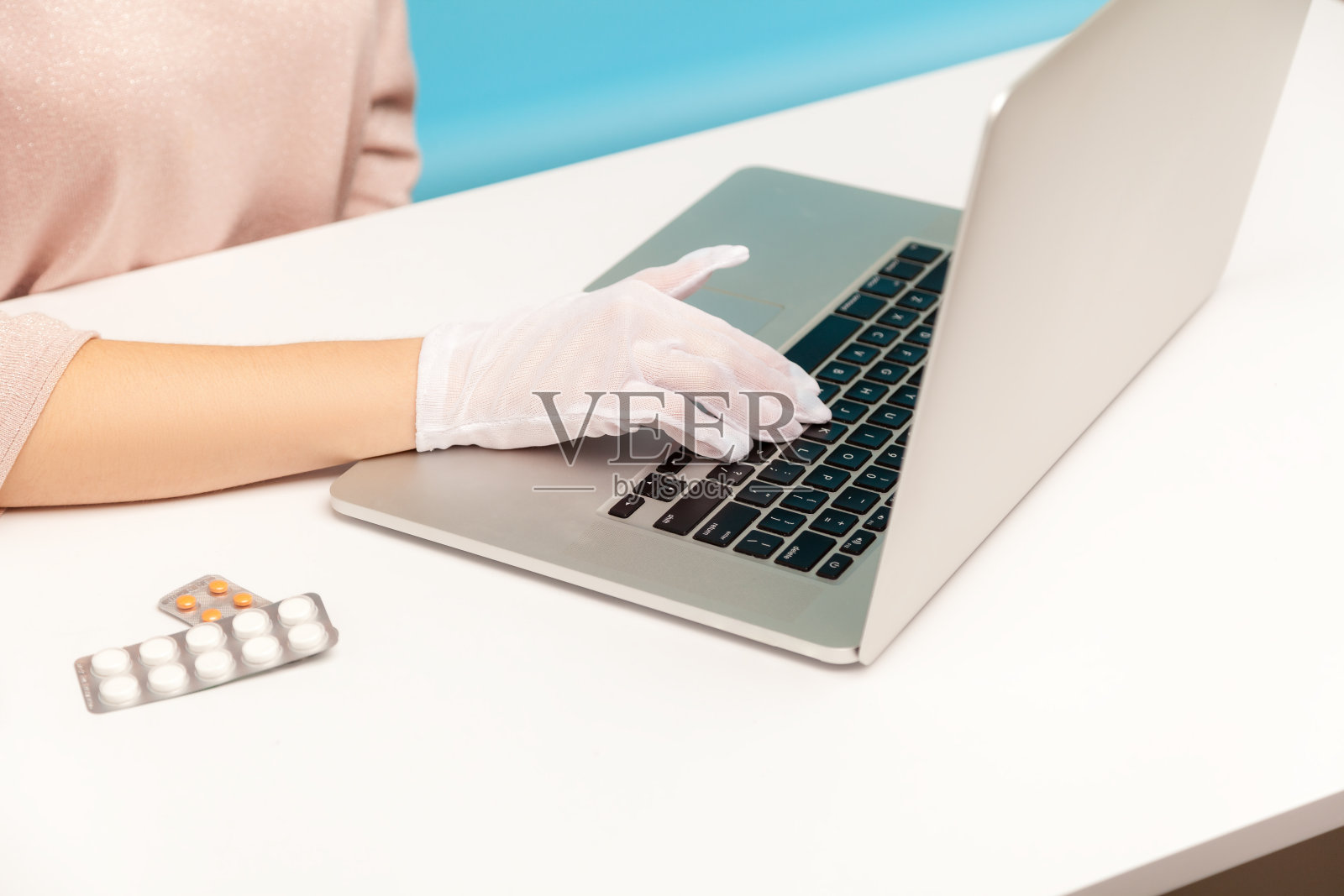 特写的女性手在笔记本电脑上的卫生手套打字，办公室员工保护她的手臂，以防止传染疾病照片摄影图片