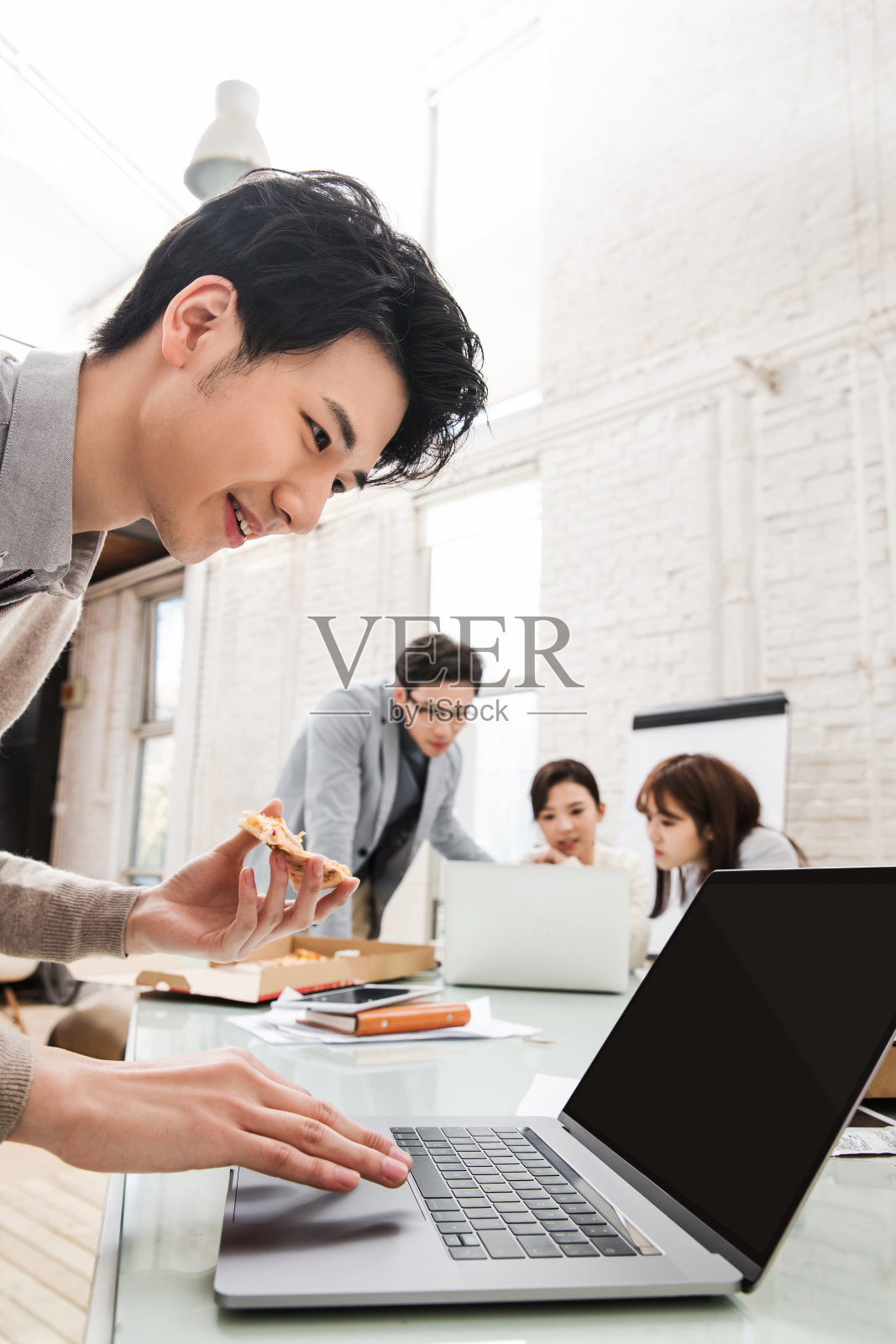 青年商务男士边吃披萨边工作照片摄影图片