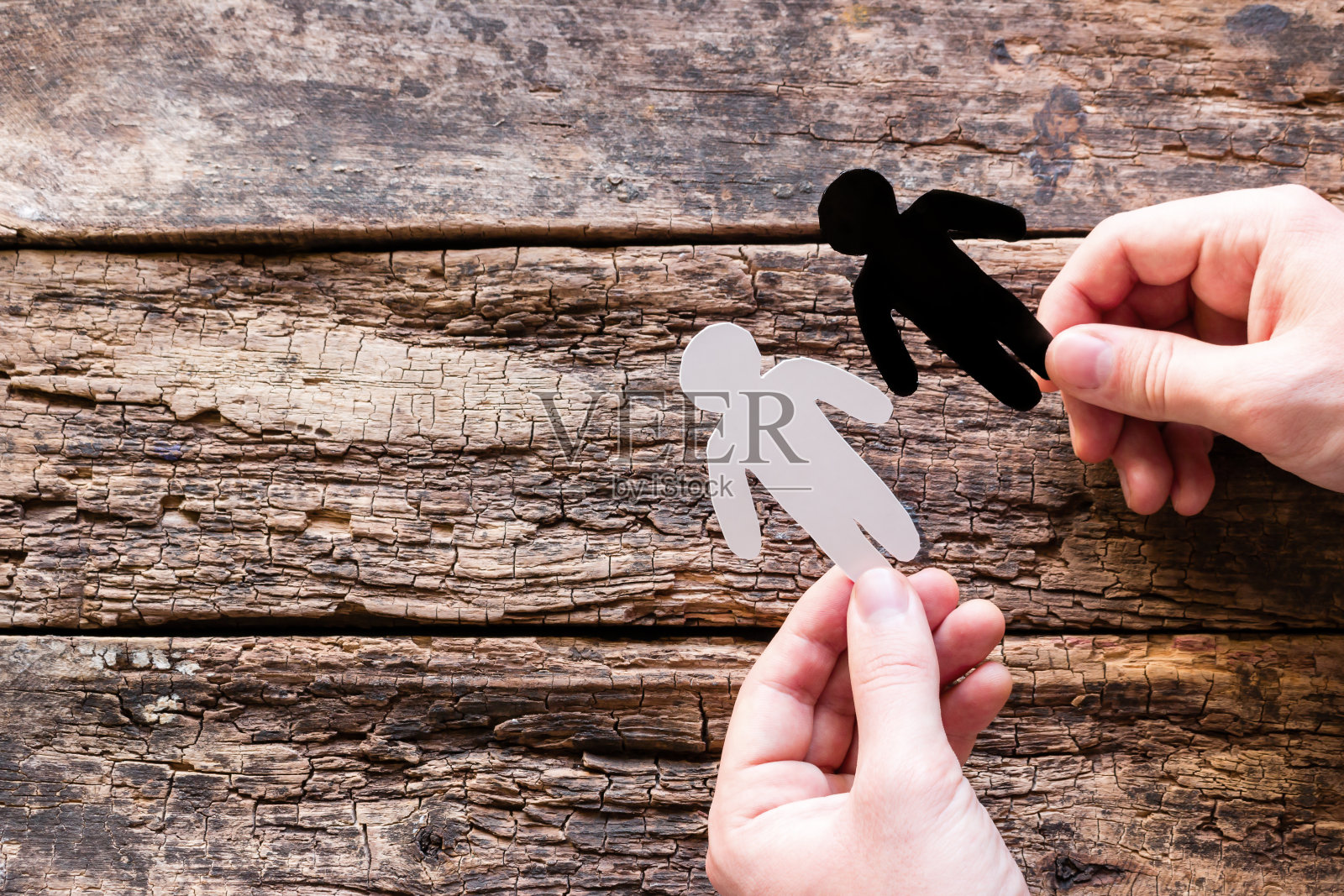 拿着黑色和白色的剪影在他的手在一个木制的背景与地方文本停止种族主义的概念照片摄影图片