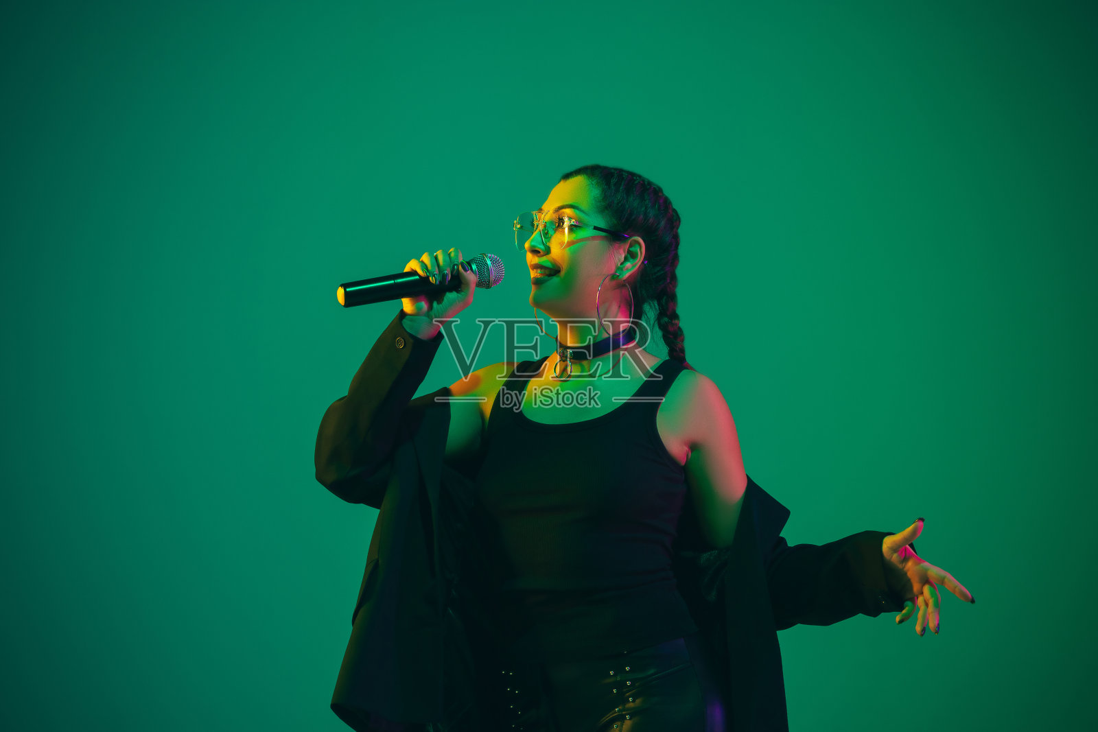 在霓虹灯下的绿色演播室背景中拍摄的白人女歌手肖像照片摄影图片