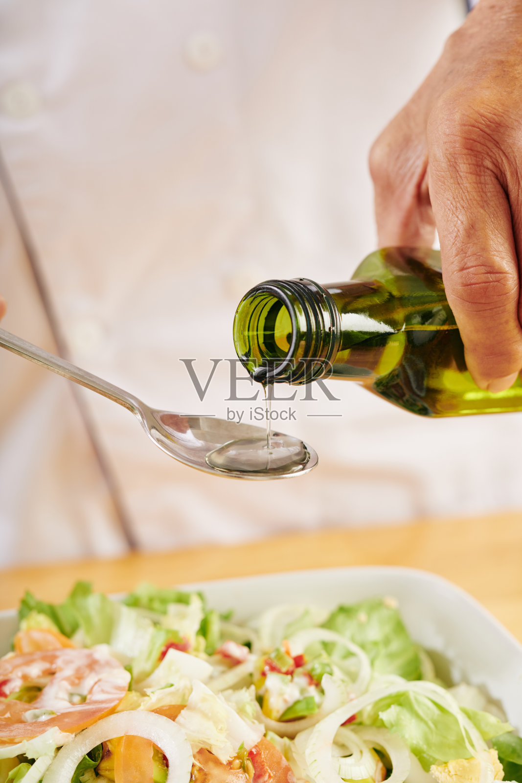 男人在沙拉中加入油照片摄影图片