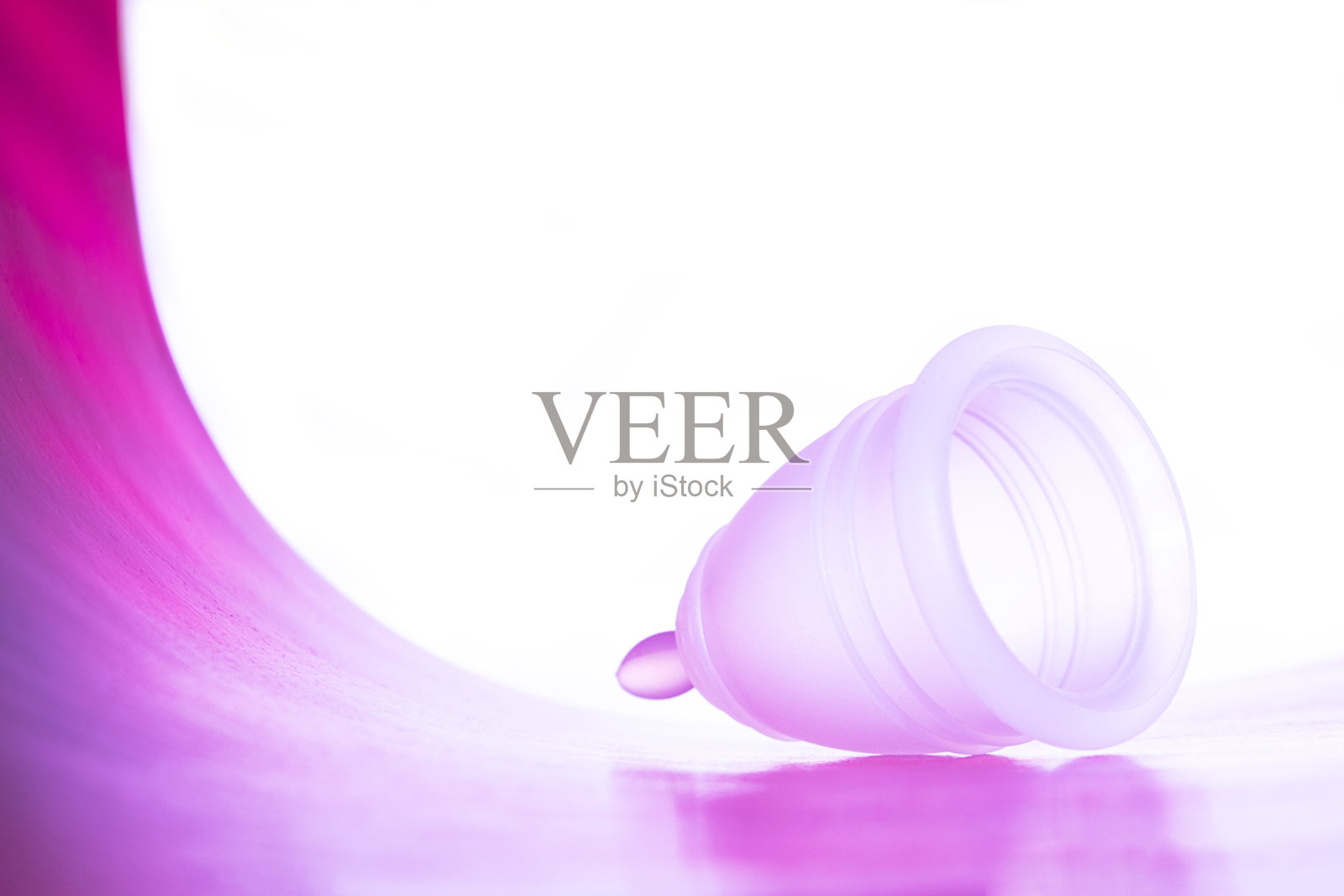 粉色可重复使用的月经杯，白色背景，淡紫色霓虹灯。照片摄影图片