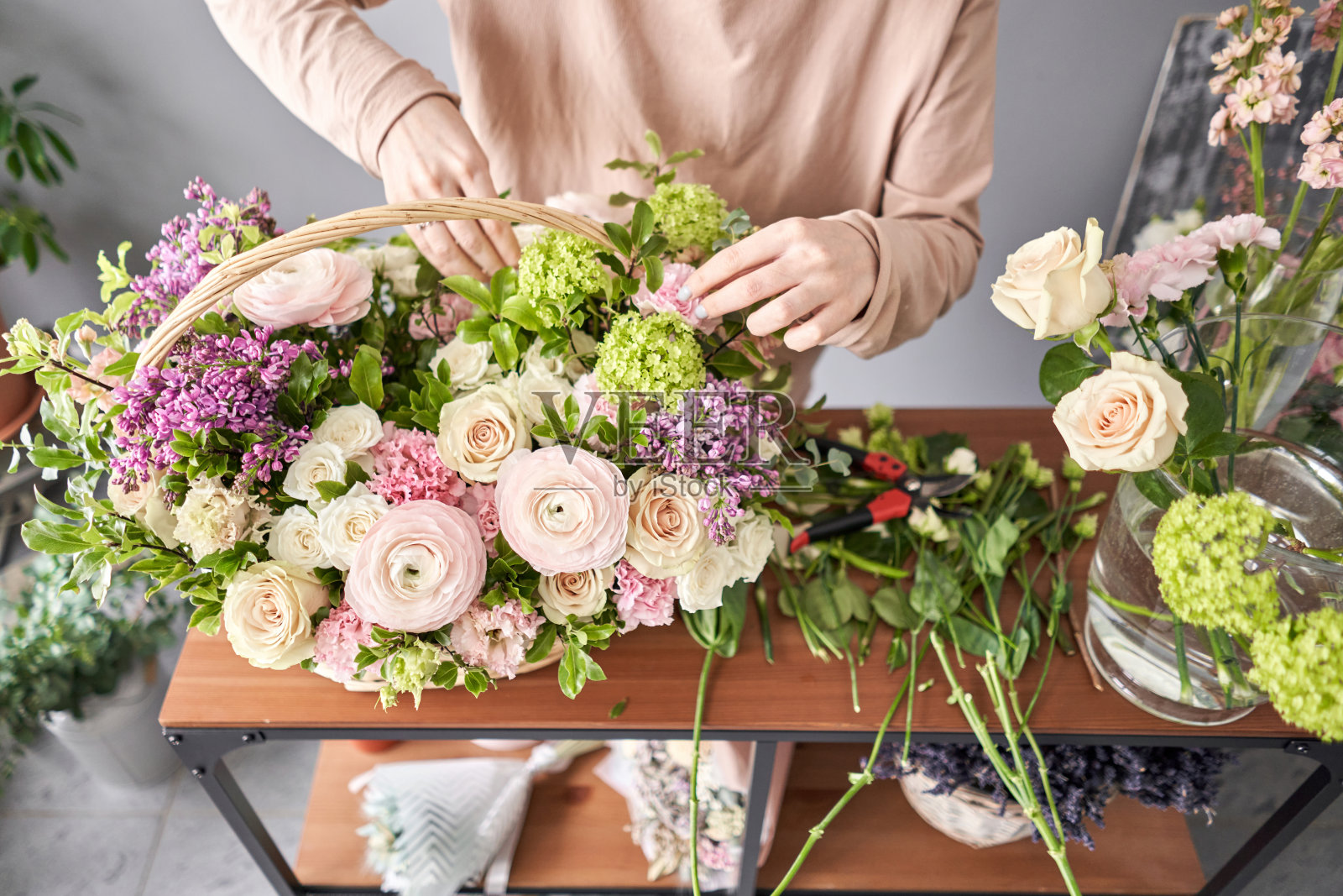 花艺学校的教育。制作花束的大师课程。柳条篮子里的夏日花束。学习插花，亲手制作美丽的花束。鲜花交付照片摄影图片