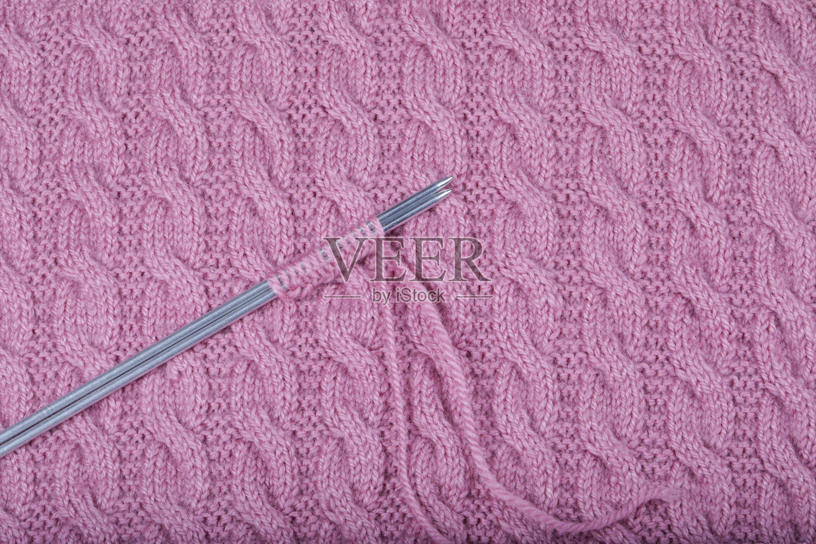 粉红色的毛线，用于编织和编织针。照片摄影图片