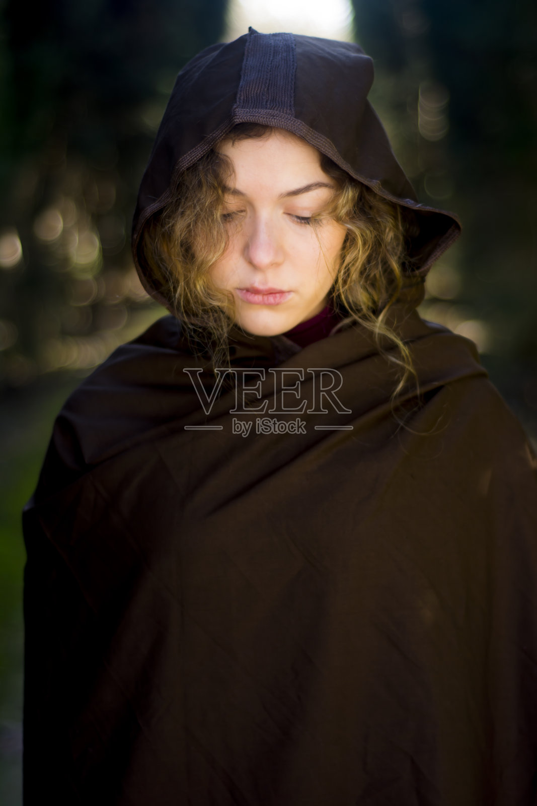 穿着斗篷的漂亮女人出现在树林里的小路上照片摄影图片