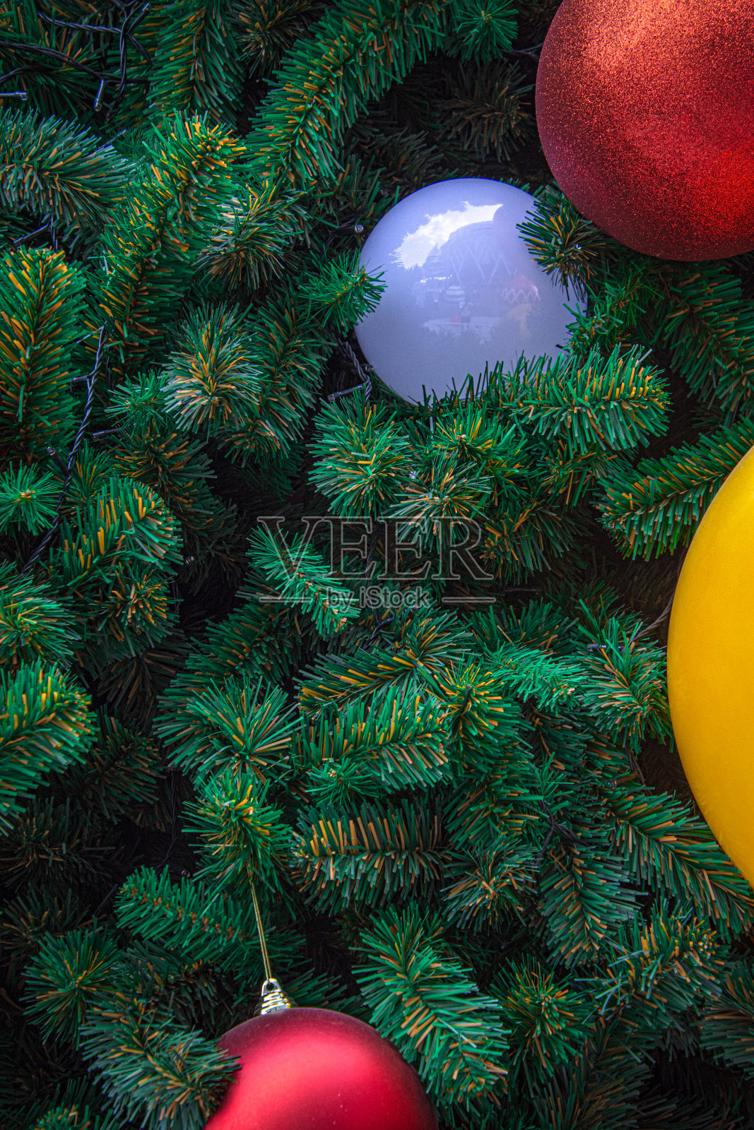 装饰圣诞树用悬挂黄色、红色和蓝色的球。照片摄影图片