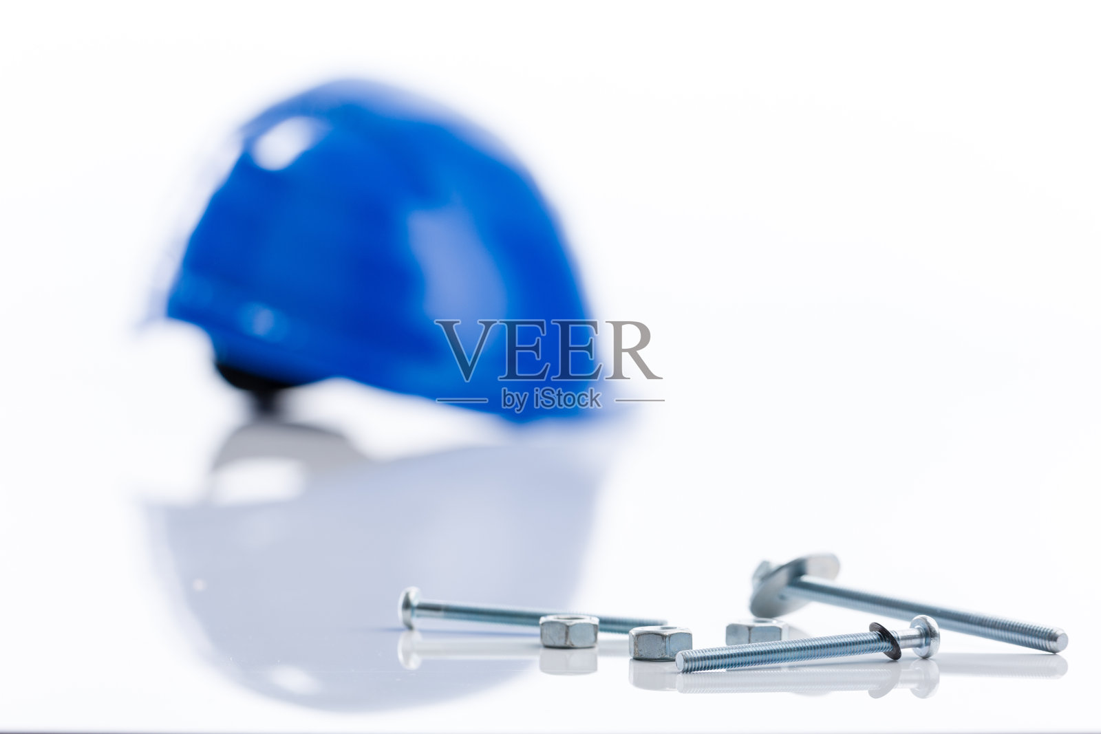 蓝色工人的安全帽和一些螺丝钉在白色的桌子上照片摄影图片