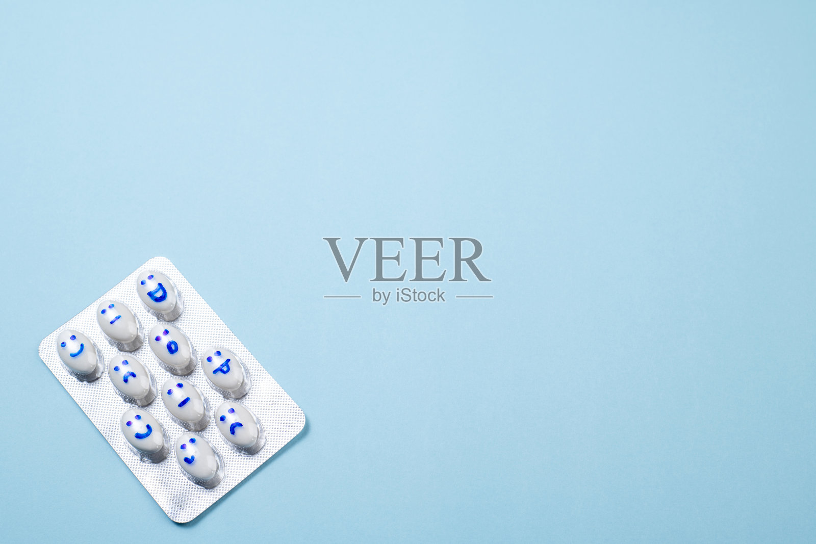 蓝色背景上的笑脸，滑稽药丸的水泡。卫生保健，每日药片，抗抑郁药，药物，治疗理念照片摄影图片