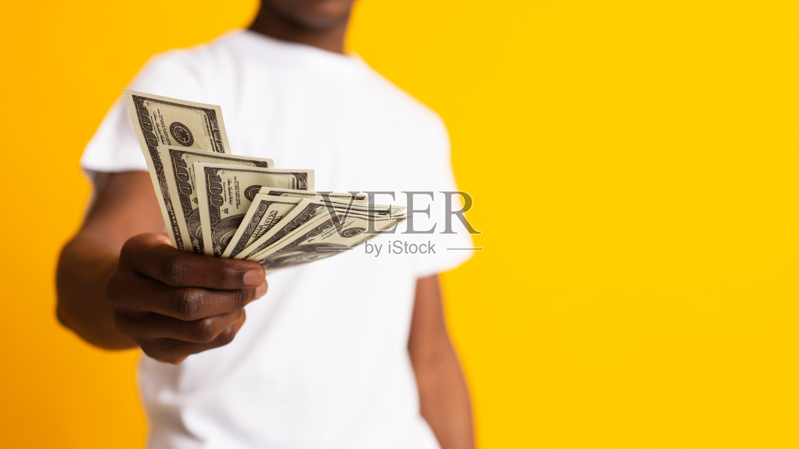 一个不认识的年轻人，手里拿着黄色钞票照片摄影图片