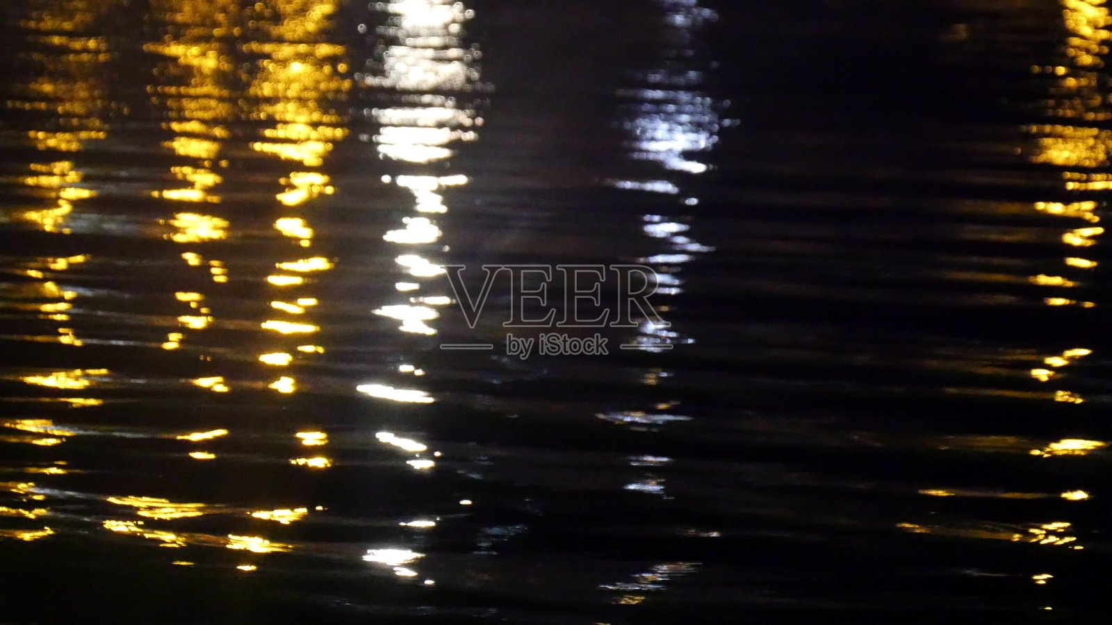 在黑暗的海面上城市照明反射的特写。照片摄影图片