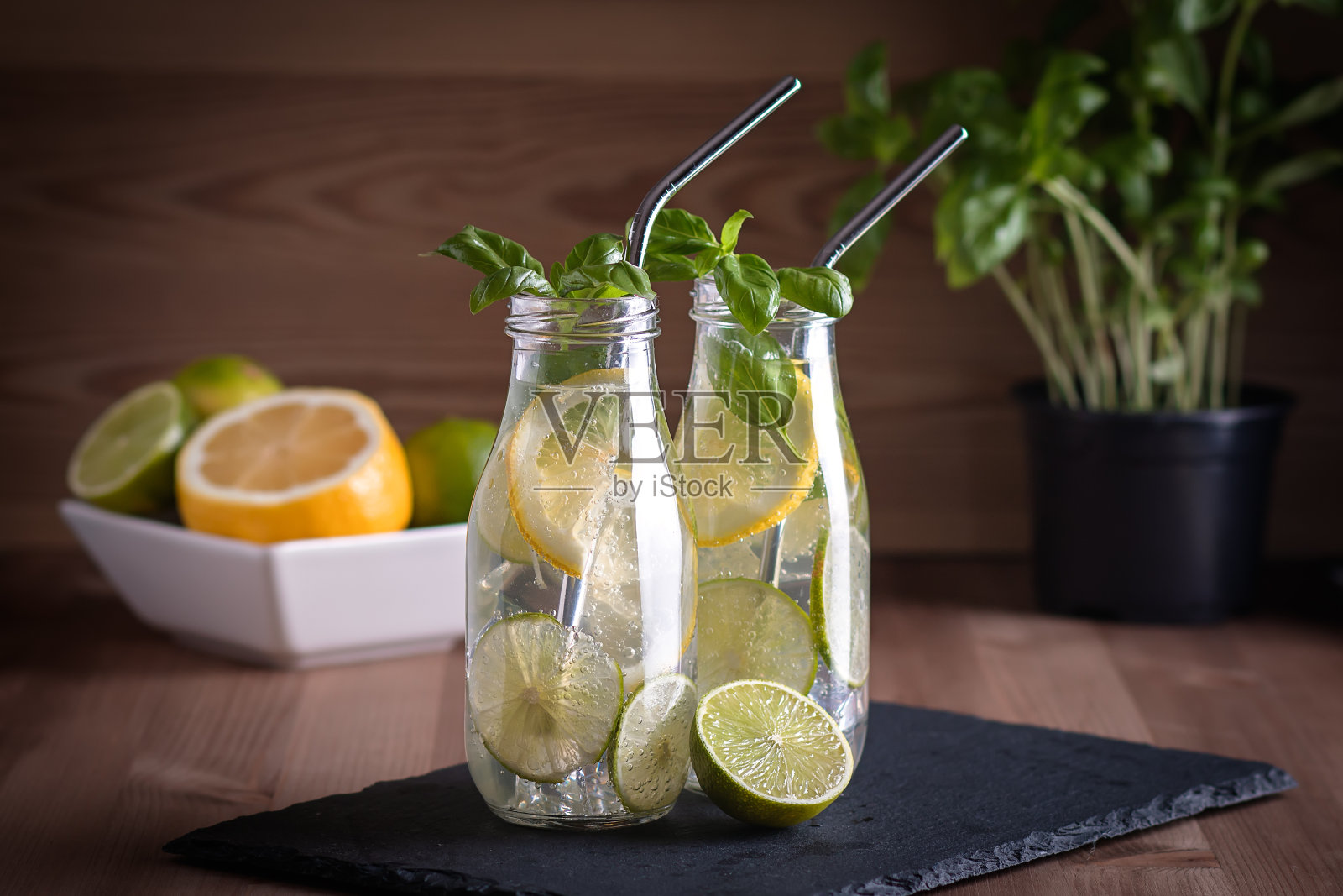 用可重复使用的金属吸管装在玻璃瓶里的清爽饮料或水，有柑橘类水果、柠檬、酸橙和罗勒香草。健康的玻璃瓶装柠檬水，零浪费理念，可持续的生活方式照片摄影图片