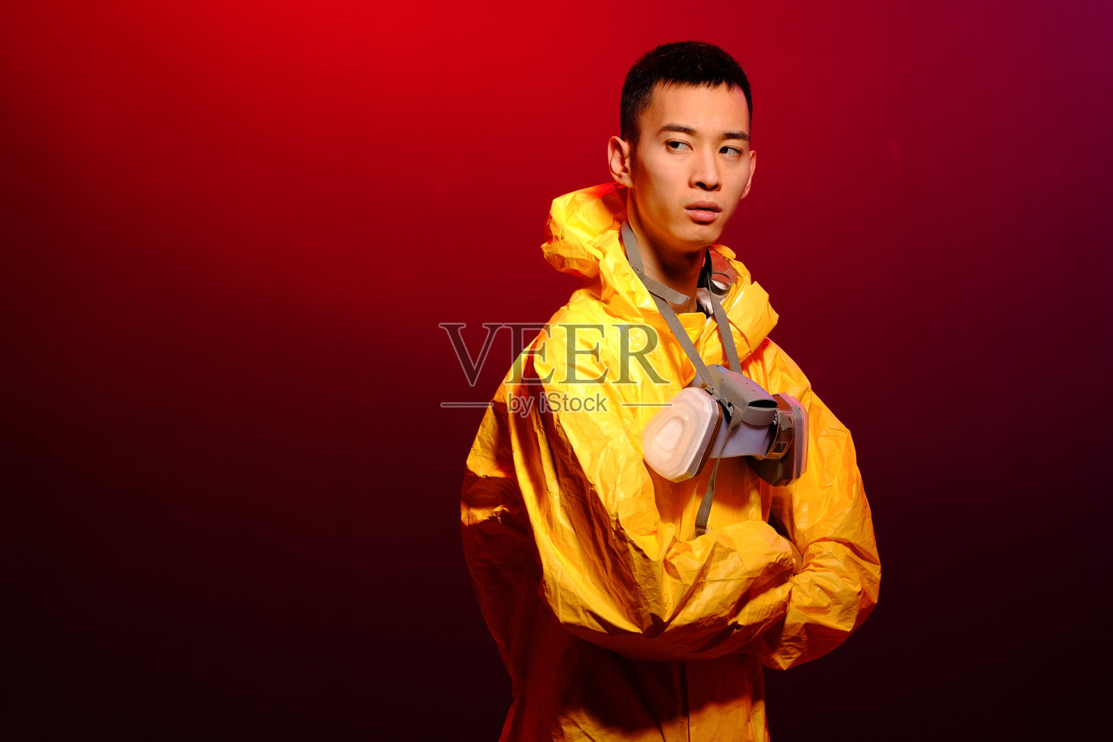 穿着化学防护黄色套装、戴着防护面具的亚洲男人，潮流彩色背景。《绝命毒师》概念照片摄影图片