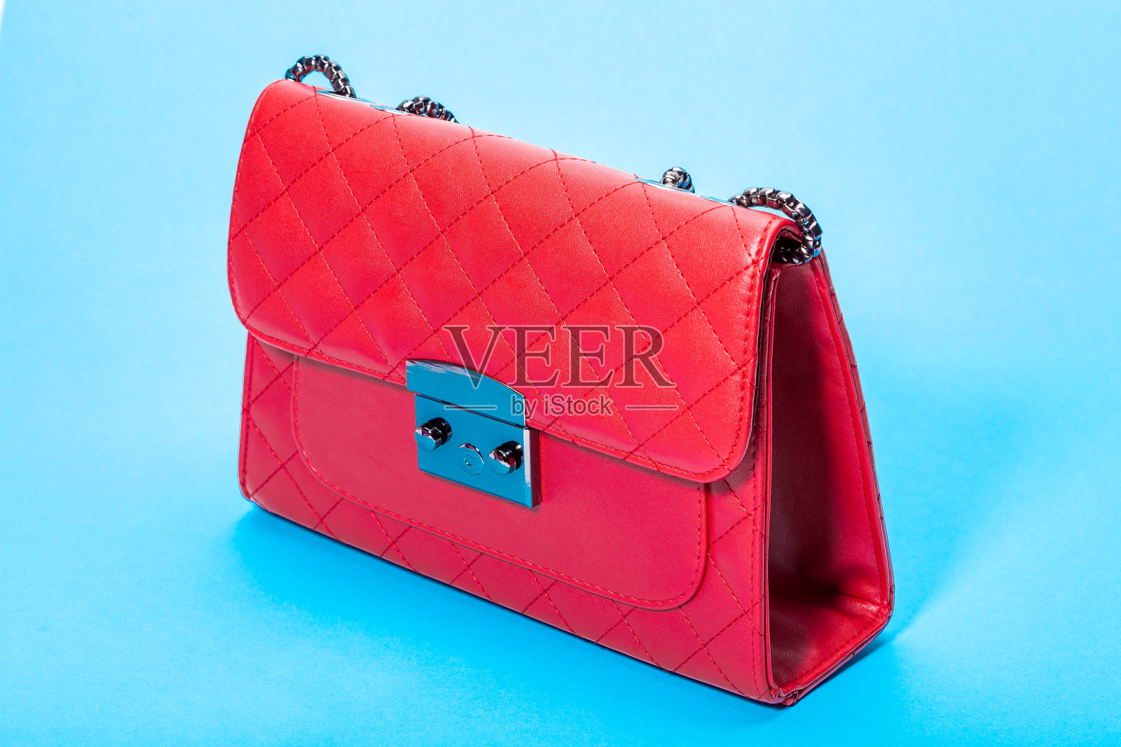 女人的手提包在红色皮革与方形图案，侧视图对象上的蓝色背景。照片摄影图片