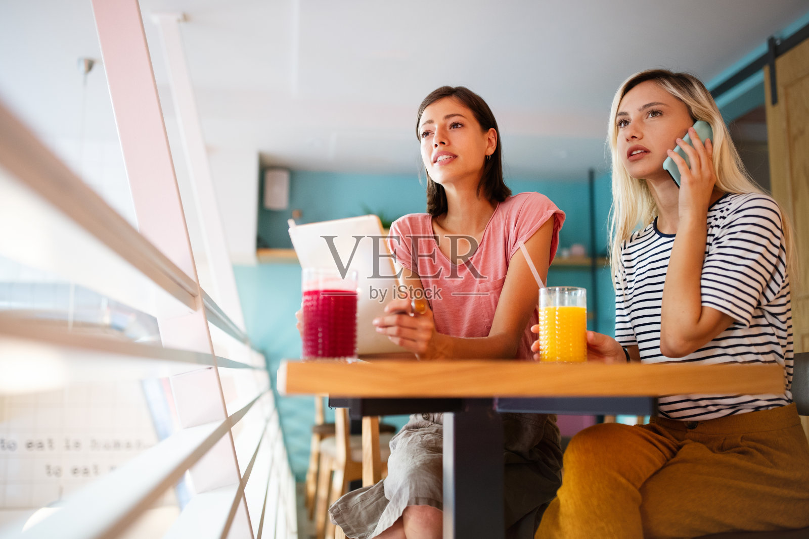 两个快乐的朋友，用笔记本电脑和手机的商业女性照片摄影图片