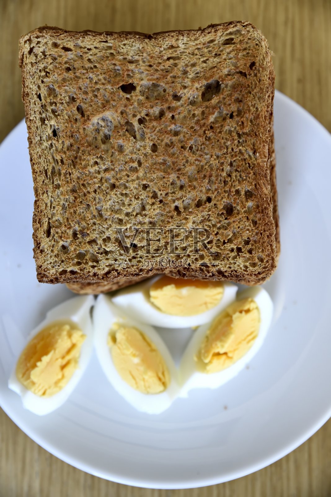 早餐：白盘上的全麦吐司和水煮蛋片照片摄影图片