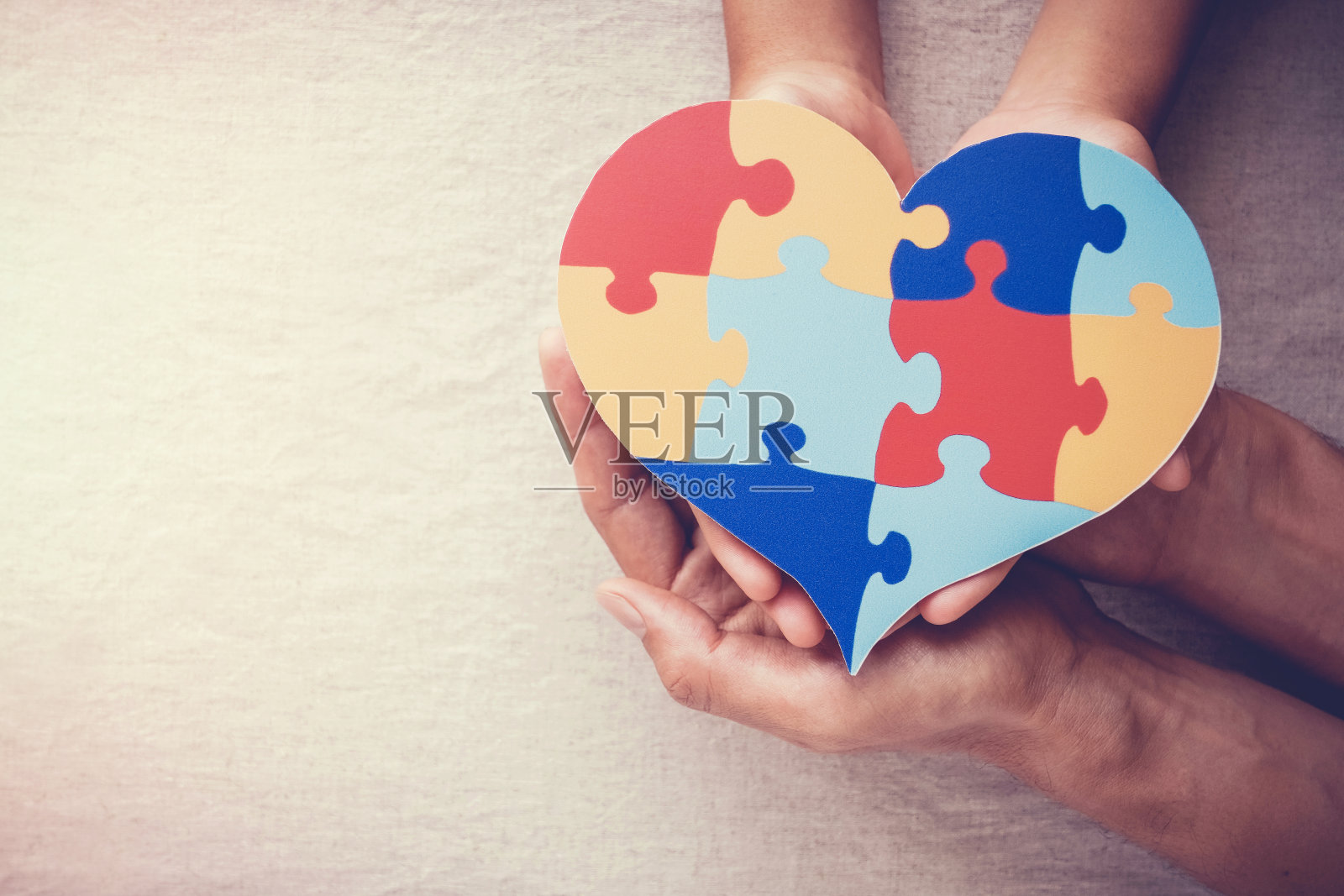 成人与儿童的手拿着拼图心，心理健康概念，世界自闭症意识日照片摄影图片