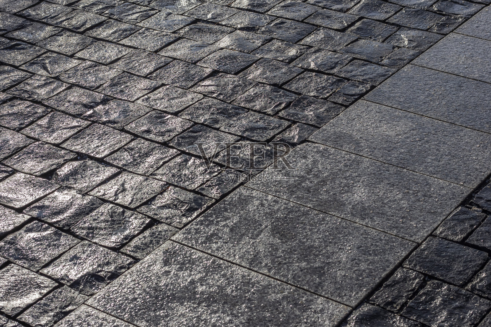 潮湿的黑色玄武岩铺在黄昏的灯光下。照片摄影图片