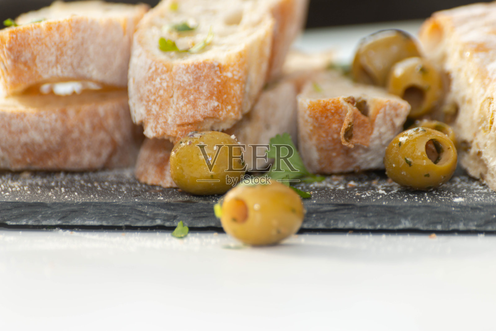 腌西班牙绿橄榄与新鲜法棍面包的特写照片摄影图片