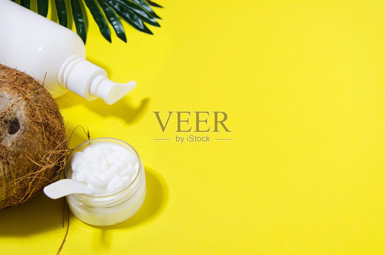 透明罐中的椰子奶油，棕榈叶上的塑料瓶装奶油照片摄影图片