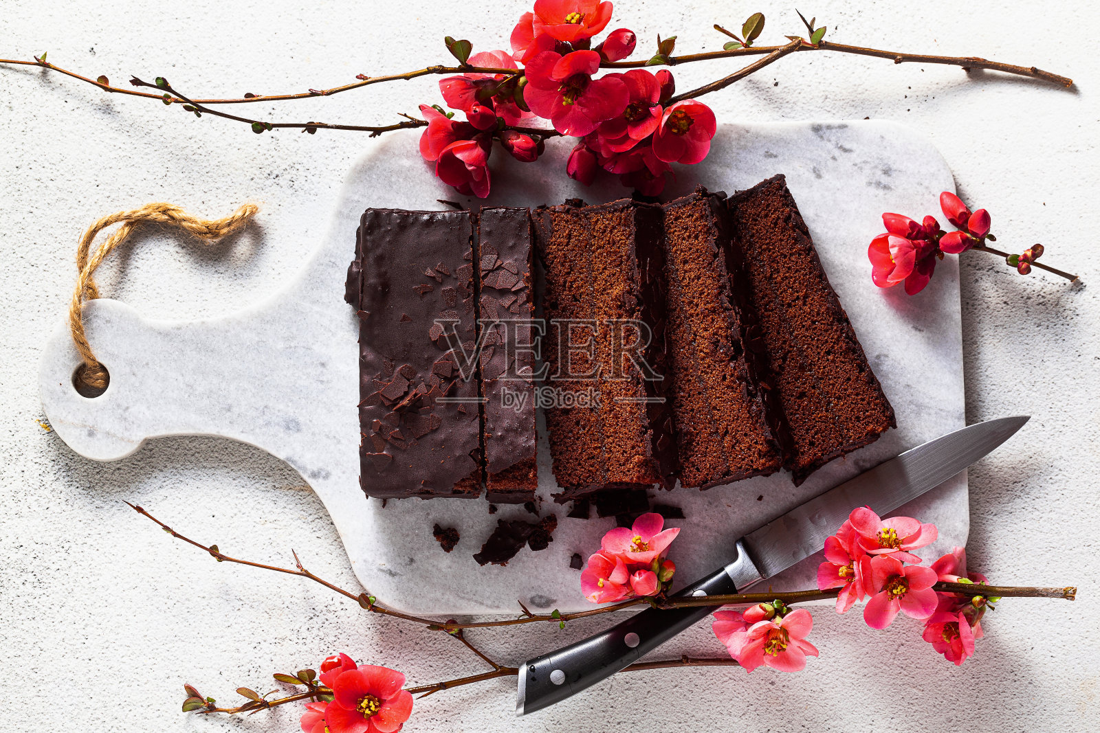 在砧板上的巧克力切片蛋糕和开花的树枝。春天的风格照片摄影图片