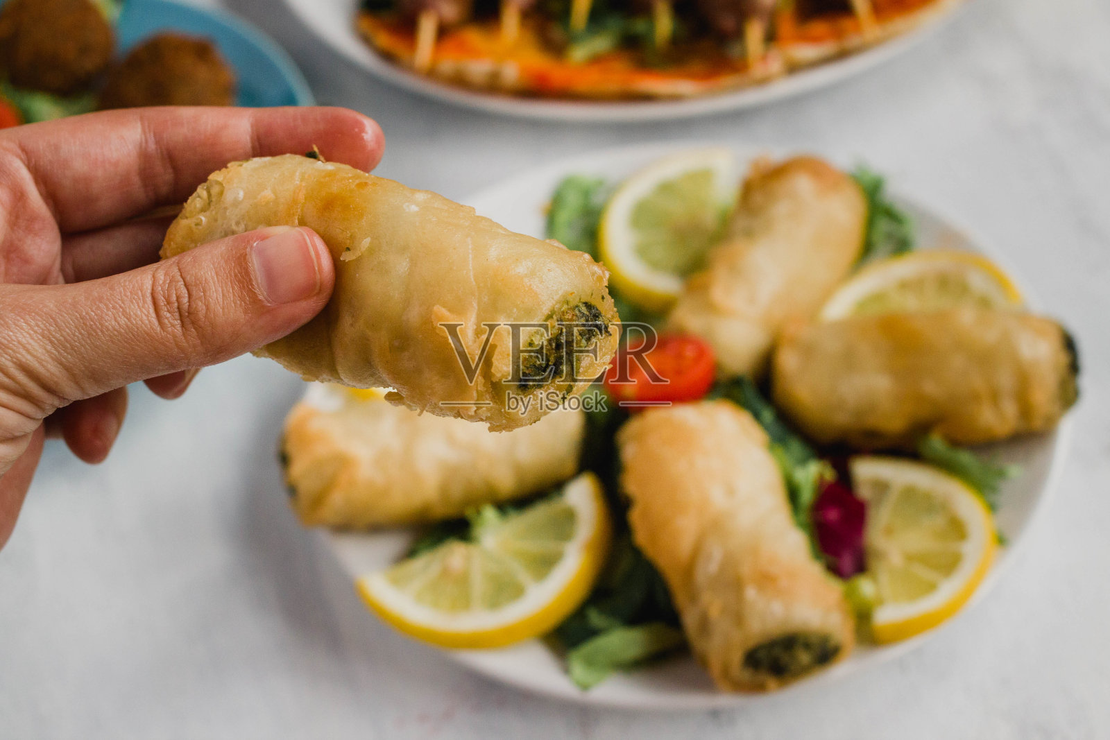 手持菠菜和奶酪肉饼卷，阿拉伯食品照片摄影图片