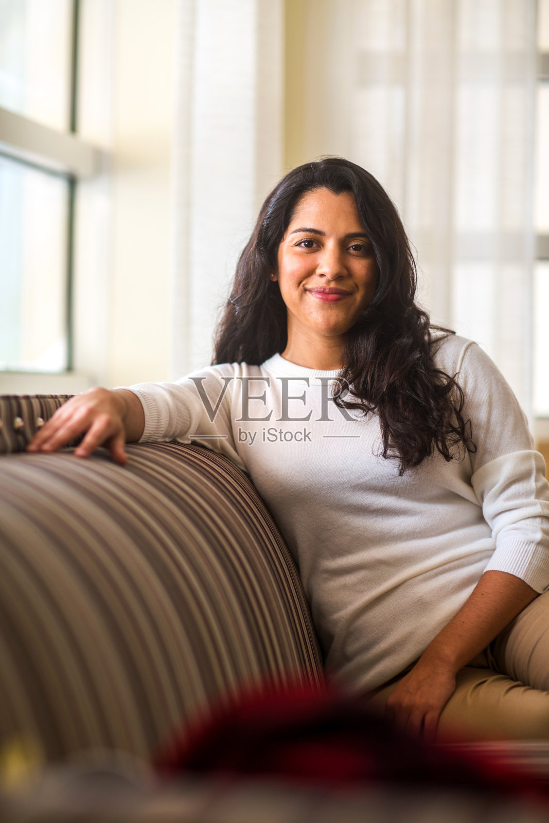 拉美裔妇女坐在沙发上微笑照片摄影图片