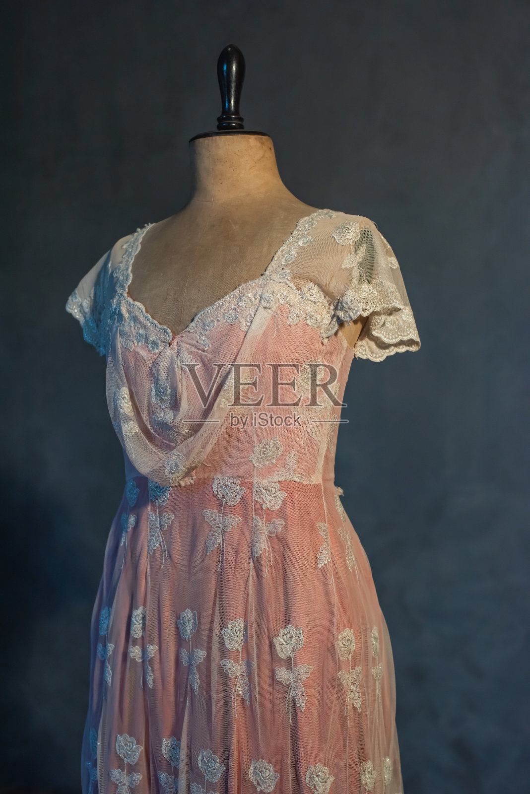 灰色的墙壁上，穿着复古模特半身裙的粉红色维多利亚式连衣裙。照片摄影图片