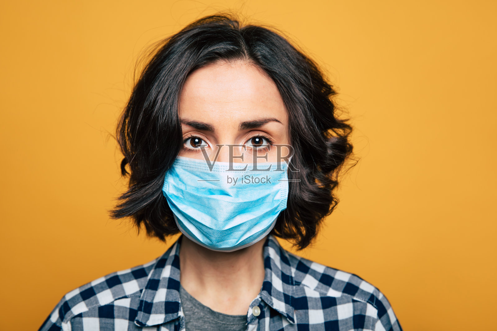 年轻严肃的女人戴着医用防护面具。照片摄影图片