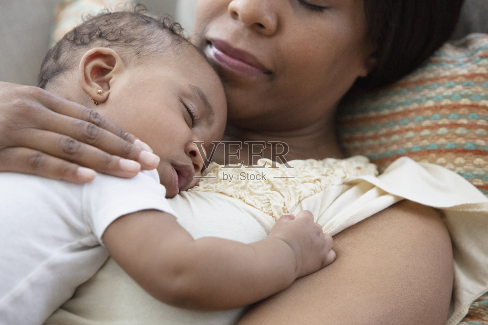 非裔美国母亲抱着婴儿睡在沙发上照片摄影图片